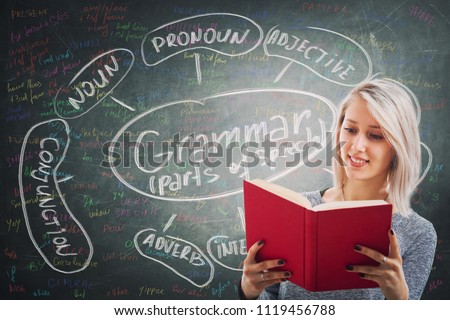 Teacher holding a red book over blackboard background written with chalk english grammar parts of speech. Opportunity for students to learn the system and structure of a language.