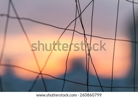 fence made of thin steel wire on blurred background