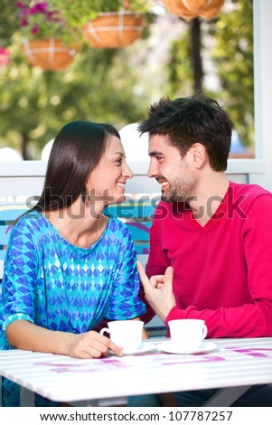 young happy couple look at each other in a cafe