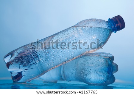 Water in bottles with drops on a surface