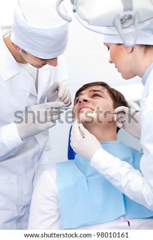 patient and two doctors with the tools in the dental office