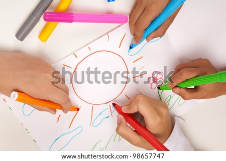 four hands holding pens on the background picture as the sun