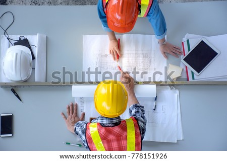 Top view of group of engineering team is meeting, planning construction work, looking paper plans at construction site, overhead view,Concept for team work