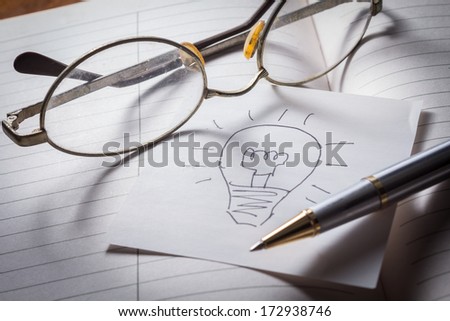 Make an idea,eyeglasses,pen and idea paper on book.