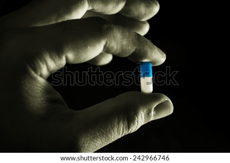 Black and white color of medicine capsule in hand.