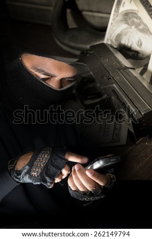 Robber man use smart phone with gun and money on background.