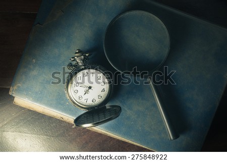 Antique book with magnifier and pocket watch,vintage filtered.