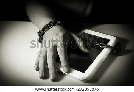 Computer tablet and human hand locked by chain,monochrome filter.