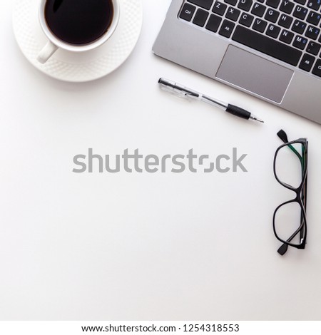 Modern white office desk table with laptop and other supplies with cup of coffee and glasses. Blank white desk for input the text in the middle. Top view, flat lay.