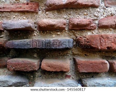 An old brick wall totes its age by means of protruding bricks.
