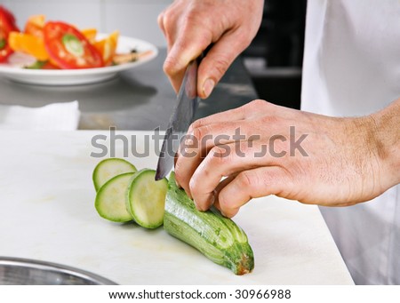 Chef carving green zucchini on professional kitchen