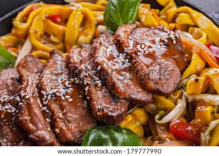 Fried duck meat with egg noodles closeup