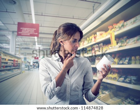 Girl unsure about the authenticity of the product at supermarket Girl unsure about the authenticity of the product at supermarket