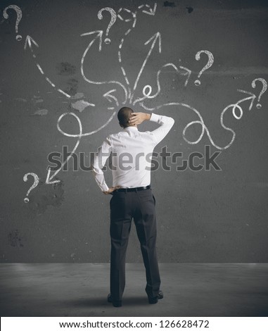 Businessman looking at arrows pointed in different directions
