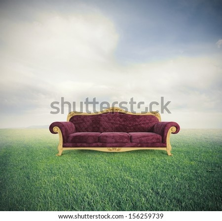 Concept Of Relax And Comfort With A Velvet Red Sofa In A Green Field