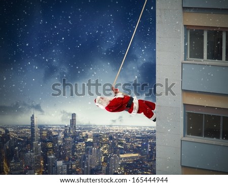 Santa Claus climbs up a building during night