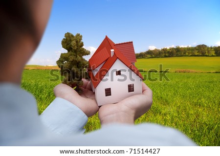 Girl hold house against green field