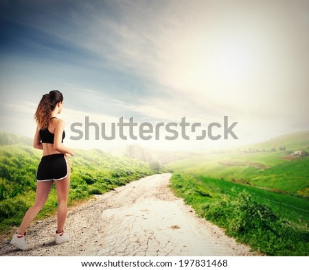 Running girl in a green field during sunrise