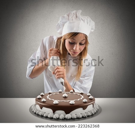 Pastry cook prepares a cake with cream and chocolate