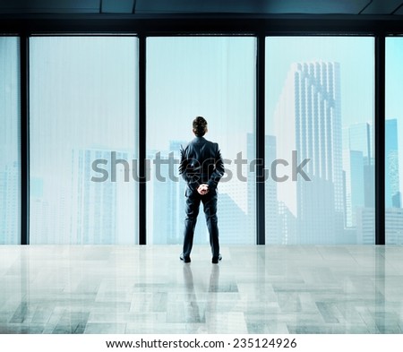 Businessman thinks about future from a skyscraper