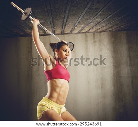 Muscular woman doing hard workout with barbell