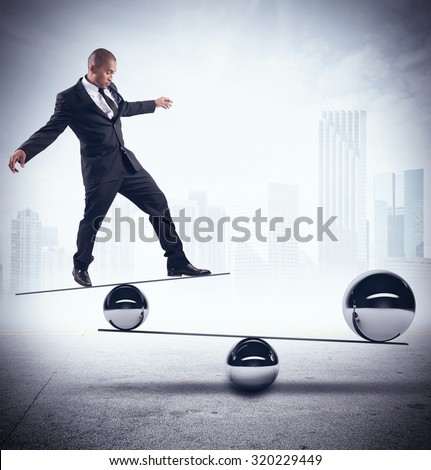Businessman balancing on boards with iron balls