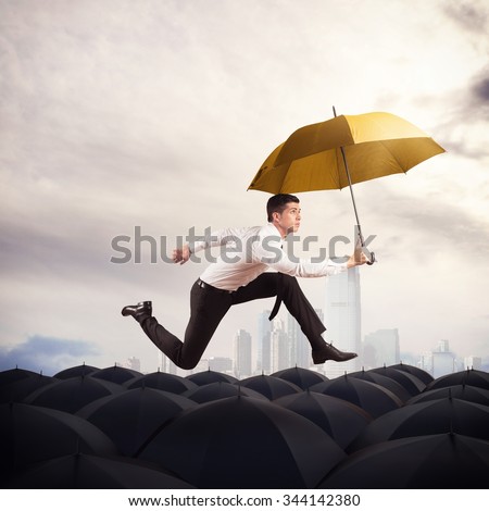 Man with yellow umbrella runs on umbrellas