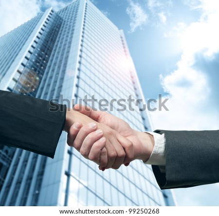 Business handshake with modern office skyscraper