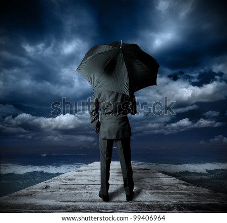 Businessman with umbrella against the storm