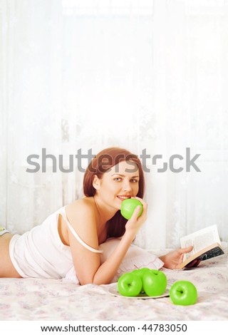 young pretty girl reading book and eat apples