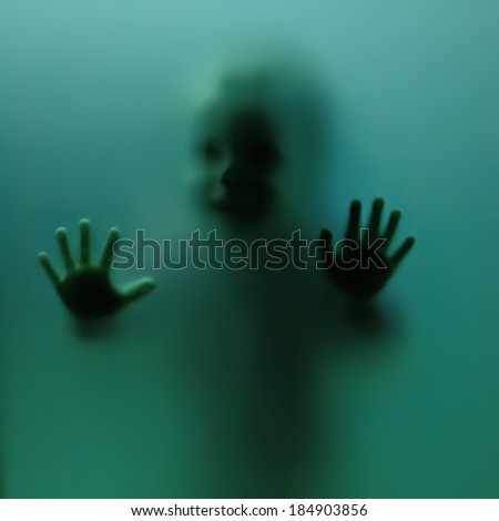 young boy behind glass trying to scare mommy