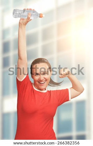 Happy smiling woman holding bottle in hand over her head and shout