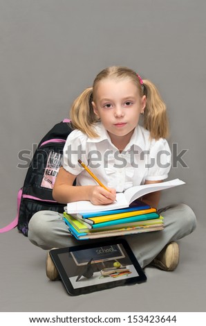 Schoolgirl with books and notebooks, tablet-makes homework.School concept