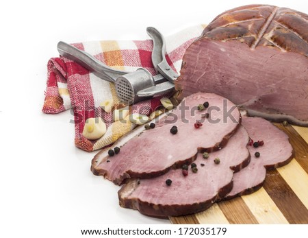 Pieces of pork on a cutting board with a tool to crush garlic.