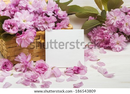 Sakura flowers in a basket  on a wooden background. Teacher Day card.