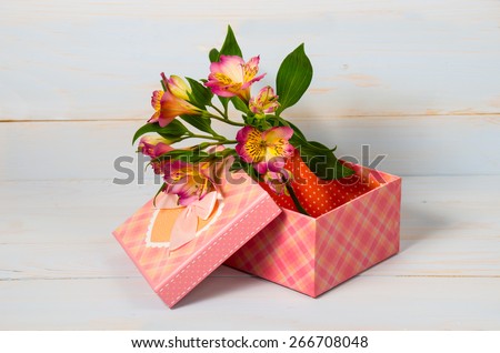 Decorative gift box with flowers on wooden background.