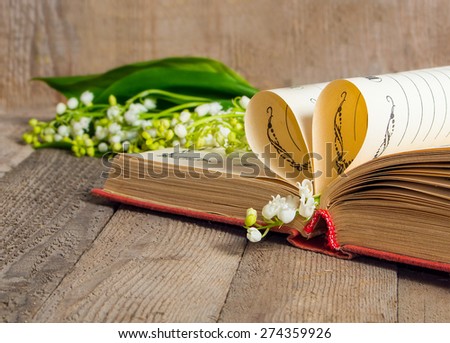 Book pages folded into a heart and a flower lily of the valley.Soft focus, deliberate slight blurring .