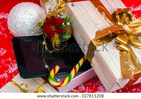 Tablet PC and candy best Christmas gift in the box on a red background