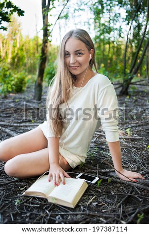 Young girl reading a book and listening to music