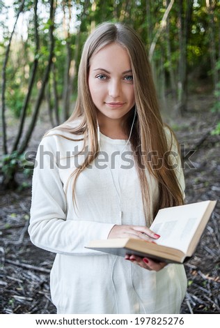 Young girl reading a book and listening to music