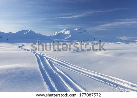 Snowmobile traces in blue mountains in Iceland./Snowmobile traces