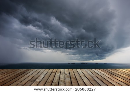 Wood decking and dark clouds before raining over the sea in Thailand