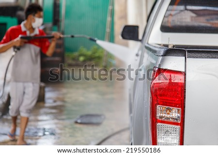 Blur of man using pressure washer for washing a car