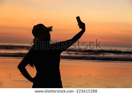 Silhouette of Thai Woman using smartphone at the beach in sunset time