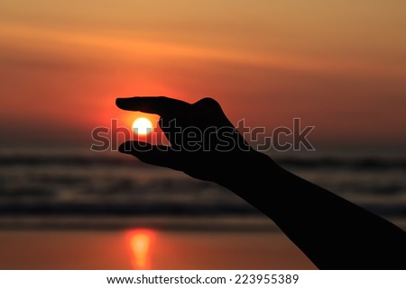 Silhouette of hands play with the sun at neach in sunset time