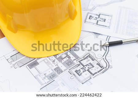 Close up Yellow safety helmet and floor plan drawings on the table