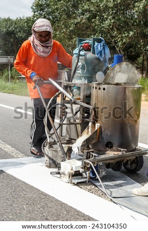 SURATTHANI, THAILAND - January 9 : Team of civil worker work on highway, they draw white line on road with eject machine January 9, 2015 in Suratthani Thailand.