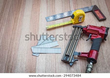 Close up air nail gun with measurement tools on wood background