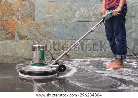 Thai people cleaning black granite floor with machine and chemical