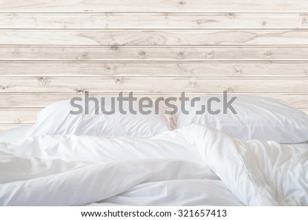 Close up white bedding sheets and pillow on wooden wall room background, Messy bed concept